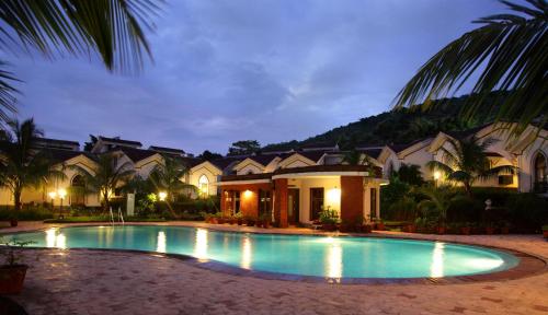 a swimming pool in front of a house at night at Riviera Foothills Duplex Apartment in Arpora