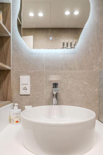 a bathroom with a white sink and a mirror at Nida Breeze Apartments in Neringa