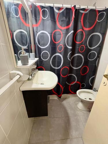 a bathroom with a shower curtain with a sink and a toilet at Alsina Mdq in Mar del Plata