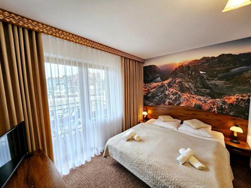 a hotel room with a bed with a large window at Willa u Zwijaczy in Zakopane