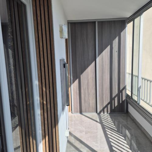 a balcony with sliding glass doors and a view of a building at Appartement neuf full équipe in Palavas-les-Flots