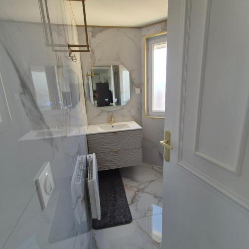 a white bathroom with a sink and a mirror at Appartement neuf full équipe in Palavas-les-Flots