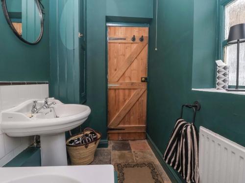 a bathroom with a sink and a wooden door at The Cooks Cottage in Malton