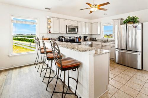 a kitchen with white cabinets and a large island with bar stools at 6170 - Poolside Paradise in Nags Head