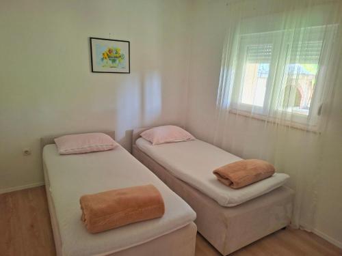 two twin beds in a room with a window at Vikendica Vlahić, Goranci in Mostar