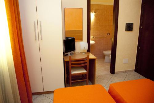 a room with a desk with a television and a bathroom at il portico dei normanni in Butera