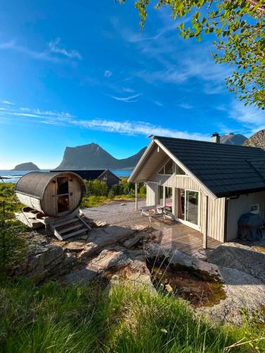a small building with a barrel next to a house at Haukland beach panorama - with Sauna in Offersøya