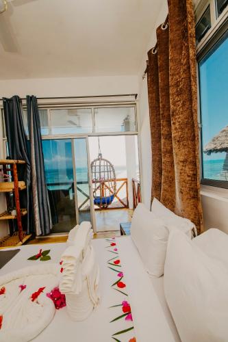 a bedroom with a white bed with flowers on it at Aquelia Rose Hotel in Jambiani