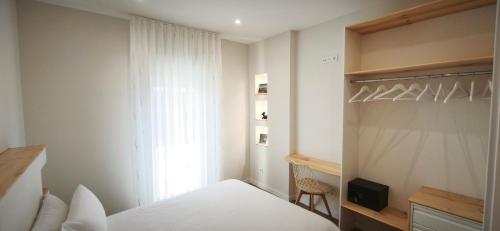 a white bedroom with a bed and a window at Pensión Vázquez in Vimianzo