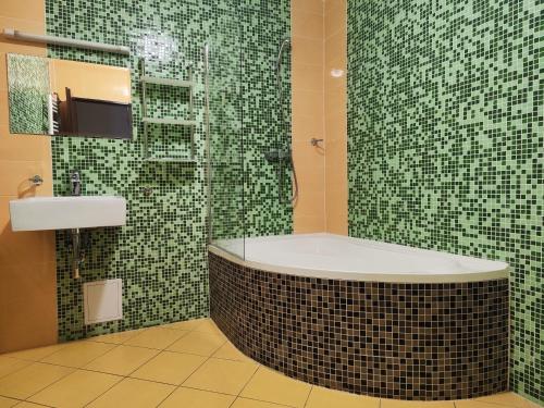 a bathroom with a tub and a shower with green tiles at Gloria in Olomouc
