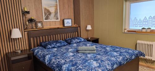 a bedroom with a bed with blue sheets and a window at Windy Guesthause in Grundarfjordur