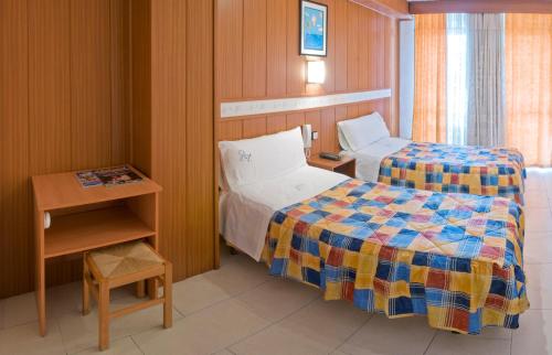 mały pokój z 2 łóżkami i stołem w obiekcie Pensión Venecia w Salou