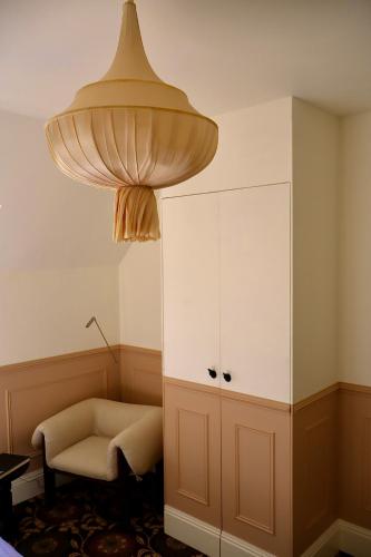 a room with a chair and a cabinet and a lamp at La Dime de Giverny - Chambres d'hôtes-Spa-Restaurant in Giverny
