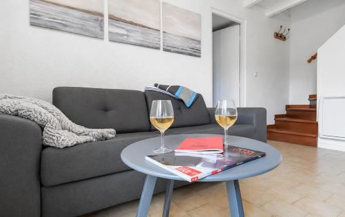 a living room with a couch and two glasses of wine at Petit cocon, parking et piscine à Marseillan in Marseillan
