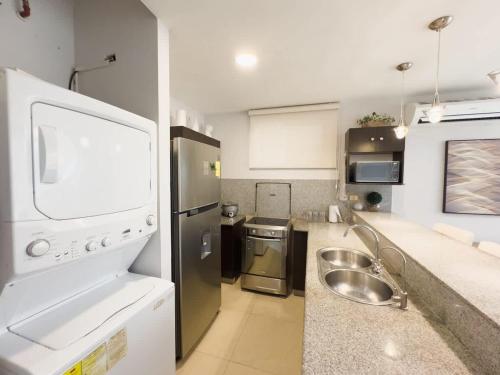 a kitchen with a sink and a stainless steel refrigerator at Amazing apartment near US Consulate in Guayaquil