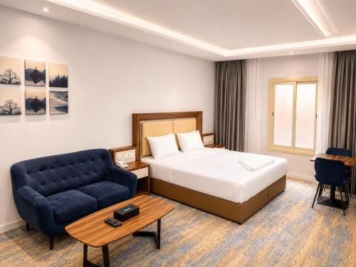 a hotel room with a bed and a blue couch at شركة نيلوفر بلس للخدمات الفندقيه in Abha