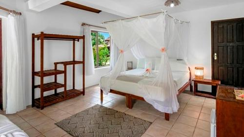 a bedroom with a bed with a mosquito net at Pousada Villa Bianca in Arraial d'Ajuda