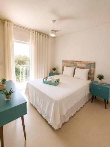 a bedroom with a large white bed and a window at casa amplia y luminosa en porto da barra in Búzios