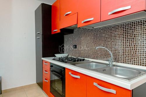 a kitchen with orange cabinets and a sink at Arabic Sea Apartments in Porto Cesareo