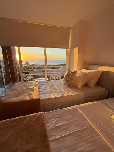 two beds in a room with a view of the ocean at Apartamento en Pampatar in Pampatar