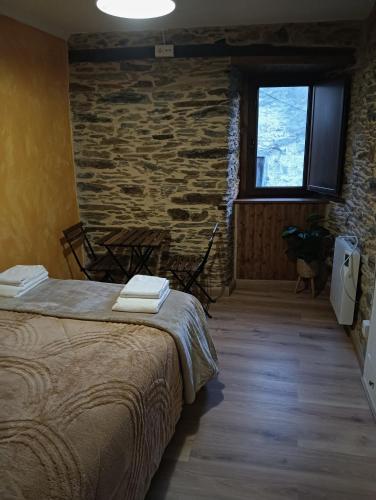 a bedroom with a bed and a stone wall at Casa da Chelo 