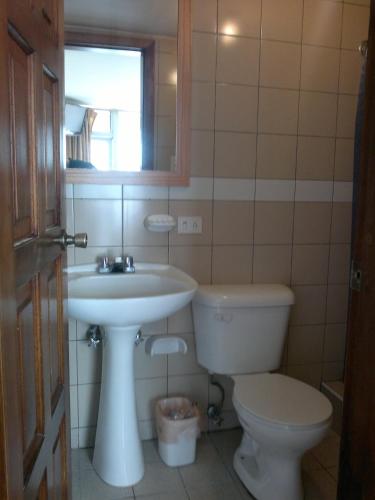 a bathroom with a sink and a toilet and a mirror at Hotel Calima in Quito