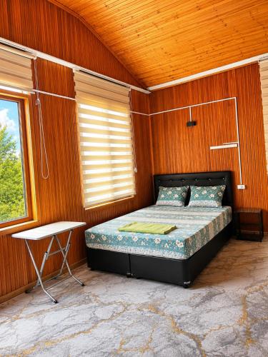 a bedroom with a bed and a table and a window at Kapuzbaşı Şelaleleri Uçar pansiyon in Büyükçakır