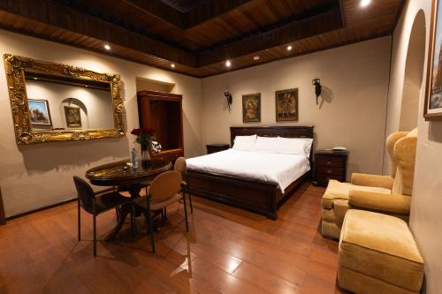 a bedroom with a bed and a table and a mirror at Hotel & Suites El Quijote in Cuenca