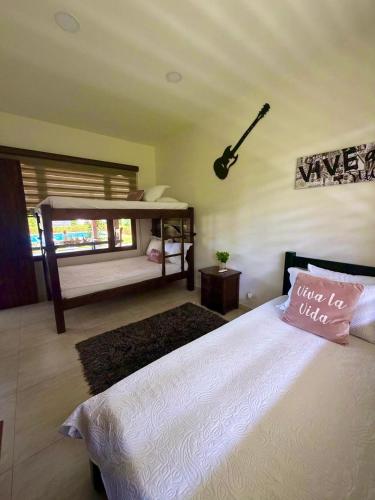 a bedroom with a bed with a guitar on the wall at Casa Carmentea Villa Privada in Acacías