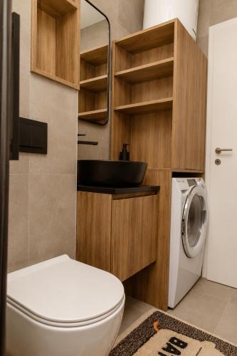 a bathroom with a toilet and a sink and a washing machine at VIP Apartman Friendly Home in Tuzla