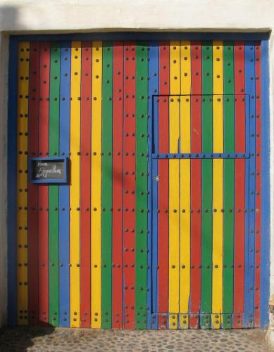 a colorful wooden door with a sign on it at Auberge De La Plage in Sidi Kaouki
