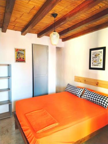 a large orange bed in a room with a wooden ceiling at Casa Naranja in Máncora