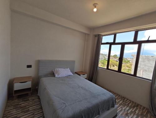 a bedroom with a bed and a large window at Casa Hormiga in Panajachel