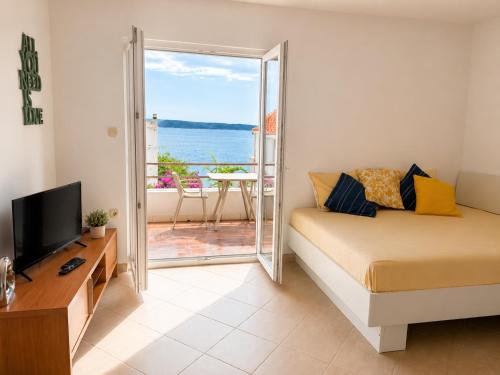 a room with a bed and a television and a balcony at Pansion Marjan in Zavala
