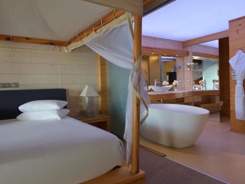 a bedroom with a bed and a bath tub at Movenpick Resort Lamantin Saly in Saly Portudal
