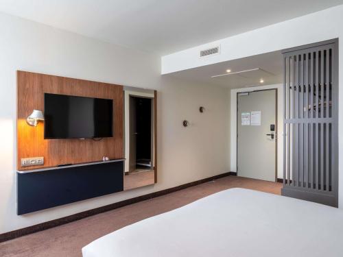 a bedroom with a bed and a flat screen tv at Ibis Rouen Centre Rive Gauche Mermoz in Rouen