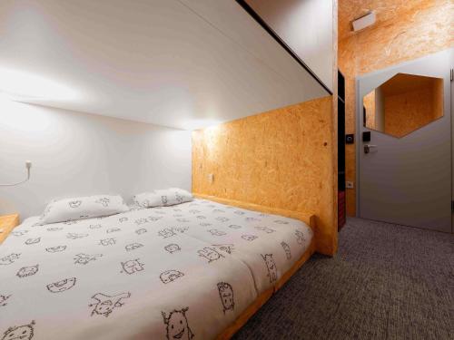 a bedroom with a large bed with white sheets at ibis Styles Ljubljana The Fuzzy Log in Ljubljana