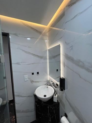 a white bathroom with a sink and a mirror at Loft Rome Nacosari in Aguascalientes