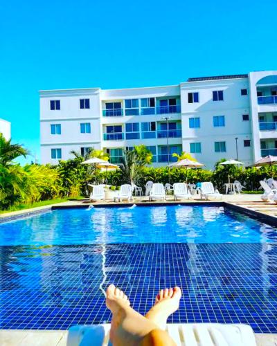 a person laying on the edge of a swimming pool at Lindo apartamento em Muro Alto, Porto de Galinhas, Vista para as piscinas, 3 qtos e sala climatizados, Acomoda até 8 pessoas in Ipojuca