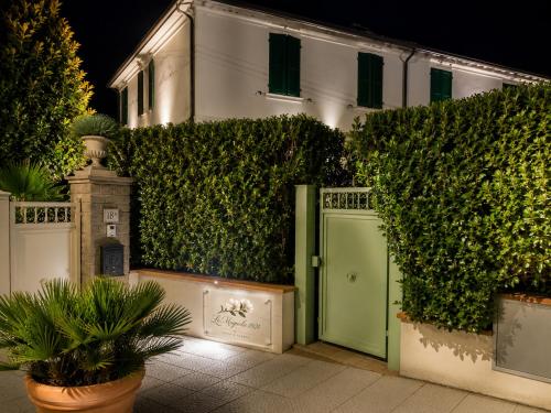a building with a green door in front of a hedge at Le Magnolie 1924 in Casciana Terme