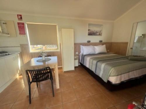 a bedroom with a bed and a table with a chair at Longreach Starlight Cabins - Boutique Outback Accommodation in Longreach