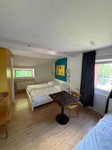a room with two beds and a table in it at Campus Hotel - ehemals Hotel Paseo in Aachen