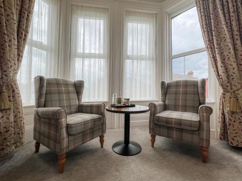 two chairs and a table in a room with windows at Somerton House Rooms Only in Belfast