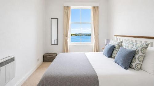 a white bedroom with a large bed and a window at Govandale Seaviews in Kingarth