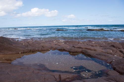 a puddle of water on the shore of the ocean at Sole's Leap in Scottburgh