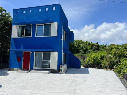 a blue house with a red door at Sun Ocean Hachijojima in Hachijo