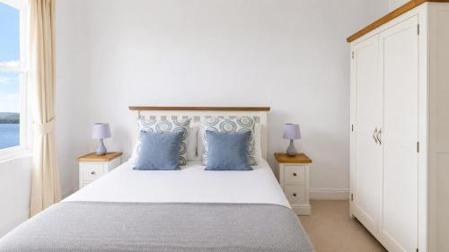 a bedroom with a white bed with blue pillows at Govandale Seaviews in Kingarth