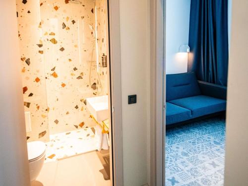 a bathroom with a blue couch next to a toilet at Ibis Styles Sibiu Arsenal in Sibiu