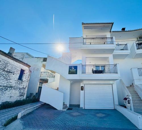 a white building with a garage in front of it at MG Sea View Apartments & Private Parking in Pefkochori