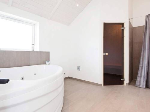 a white bathroom with a large tub and a window at Luxury Retreat with Spa - By Traum Ferienwohnungen in Bøtø By